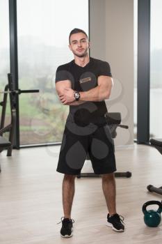 Handsome Personal Trainer With Stopwatch In A Fitness Center Gym Standing Strong