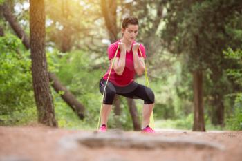 Young Woman Exercise with Resistance Band in Wooded Forest Area - Fitness Healthy Lifestyle Concept