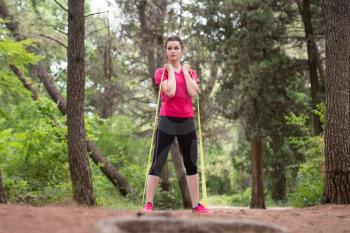 Young Woman Exercise with Resistance Band in Wooded Forest Area - Fitness Healthy Lifestyle Concept