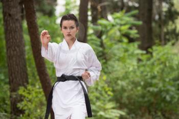 Young Woman Practicing Her Karate Moves in Wooded Forest Area - White Kimono - Black Belt