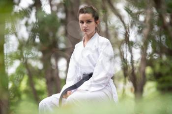 Woman Dressed In Traditional Kimono Resting After Practicing Her Karate Moves In Wooded Forest Area