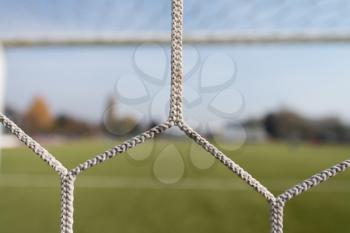 Soccer or Football Net Background - View From Behind the Goal With Blurred Stadium and Field Pitch