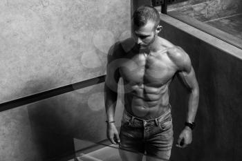 Portrait of a Young Physically Fit Man Showing His Well Trained Body While Wearing Blue Jeans - Muscular Athletic Bodybuilder Fitness Model Posing After Exercises on Wall Near the Wall - a Place for Your Text