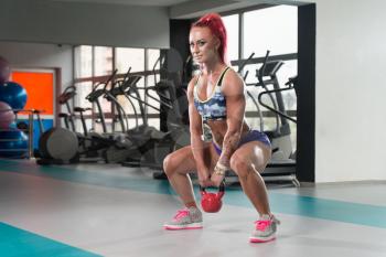 Young Woman Working Out With Kettle Bell In A Dark Gym - Fitness Doing Heavy Weight Exercise With Kettle-bell