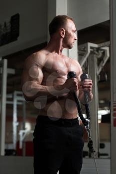 Muscular Fitness Bodybuilder Doing Heavy Weight Exercise For Biceps On Machine With Cable In The Gym