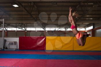 Female Athlete Performing a Long Jump in Gym - One of the Best Jumping Exercise for Vitality