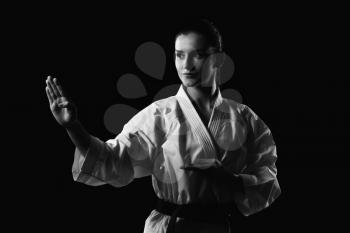 Young Muslim Woman In Traditional Kimono Practicing Her Karate Moves - Isolated On Black Background