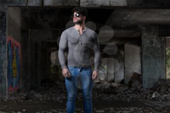 Portrait of a Young Physically Fit Man in Grey Long Sleeve Shirt Showing His Well Trained Body - Muscular Athletic Bodybuilder Fitness Model Posing After Exercises In Front Of A Graffiti Wall