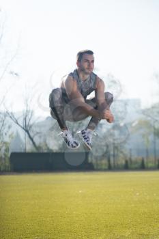Attractive Man Doing Jumping in City Park Area - Training and Exercising for Endurance - Fitness Healthy Lifestyle Concept Outdoor