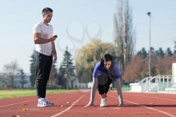 Handsome Personal Trainer Helping Woman To Sprint on the Running Track in City Park Area - Training and Exercising for Endurance - Healthy Lifestyle Concept Outdoor
