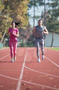 Attractive Couple Sprinting on the Running Track in City Park Area - Training and Exercising for Endurance - Fitness Healthy Lifestyle Concept Outdoor