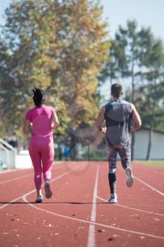 Attractive Couple Sprinting on the Running Track in City Park Area - Training and Exercising for Endurance - Fitness Healthy Lifestyle Concept Outdoor
