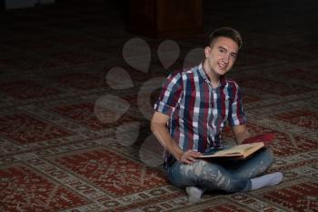 Young Muslim Man Is Reading The Koran In The Mosque