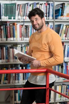 In the Library - Handsome Male Student With Books Working in a High School - University Library - Shallow Depth of Field