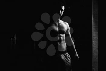 Portrait Of A Physically Fit Man Showing His Well Trained Body In Dark Room