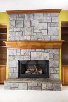 Natural Gas fireplace built with stone and wooden mantels in family room of modern home