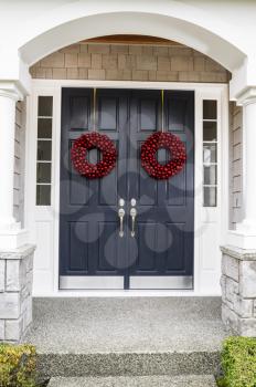 Front entrance of home door decorated with red ball wreaths for the holiday