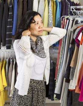 Vertical portrait of mature Asian woman in walk-in closet putting on her scarf