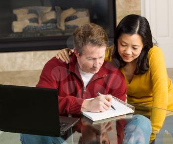 Photo of mature couple closely working together at home with fireplace in background  