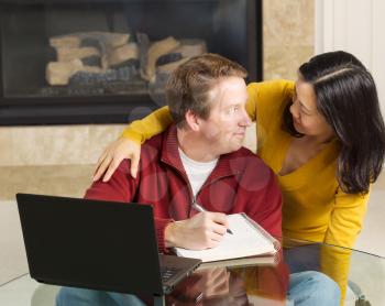 Photo of close mature couple looking at each other while working from home with fireplace in background  
