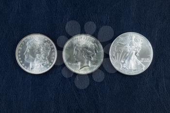 Closeup horizontal photo of a Morgan, Peace and American Silver Eagle Dollars on Blue Vinyl Holder  