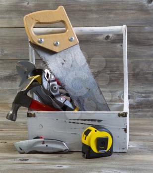 Vertical view of an old tool holder containing basic home repair tools on rustic wooden boards
