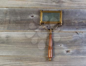 Horizontal view of an antique rectangular shaped magnifying glass on rustic wood 