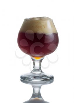 Fresh dark beer in glass goblet on white with reflection