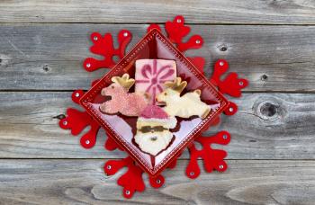 Top view of Christmas cookies in plate and large red snowflake with rustic wood underneath