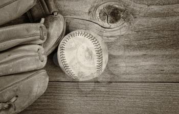 Vintage concept of old baseball and mitt on rustic wood. Layout in horizontal format. Slight vignette on border. 