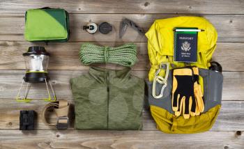 High angled view of organized hiking gear for climbing placed on rustic wooden boards. 