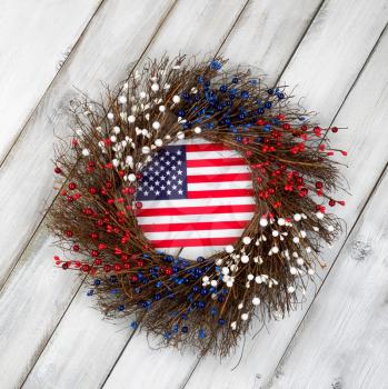 Wreath decorated for Independence Day with USA flag inside on rustic white wooden boards.