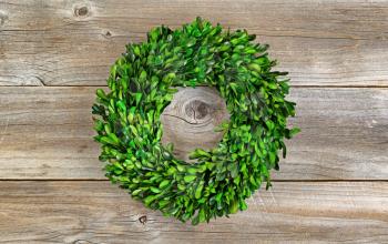 Wreath made with real natural green boxwood leaves on rustic wood. 
