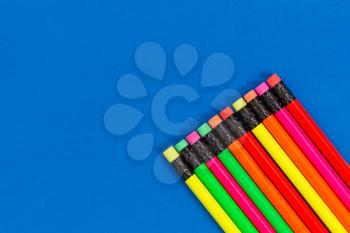 
Office or back to school supplies consisting of colorful pencils in lower right corner on blue background.  
