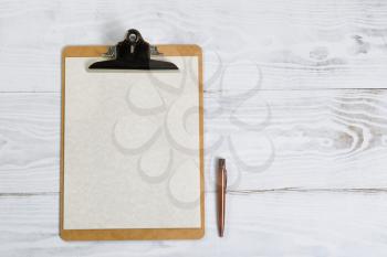 Top view of clipboard with antique pen, paper on white desktop. 