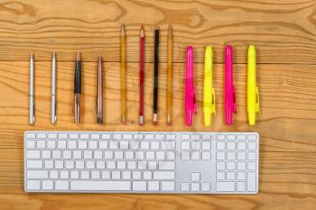 Top view of organized writing tools with generic keyboard. 