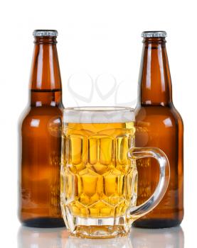 Golden colored beer in stein with two full bottles in background. Isolate on white with reflection. 