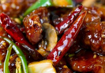 Chinese hot red Chile peppers with chicken and vegetables. Filled frame format with selective focus on front pepper. 