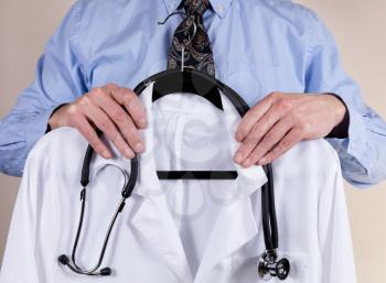 Close up partial view of medical doctor holding consultation white coat with stethoscope in front of him. 