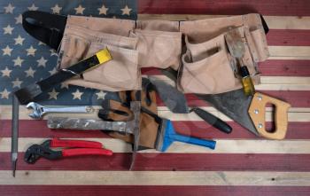 Labor Day background with USA rustic wooden flag and used industrial tools plus utility belt 