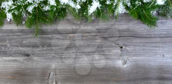 Overhead view of snow covered Christmas fir tree branches on weathered wood for holiday concept 