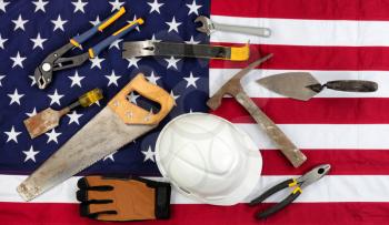 Labor Day holiday background with cloth USA flag and various worker tools