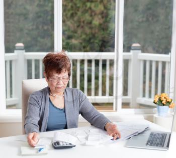 Senior woman looking frustrated while working on her financial bills 