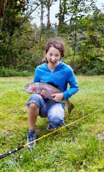 Teen girl holding large trout with big smile 