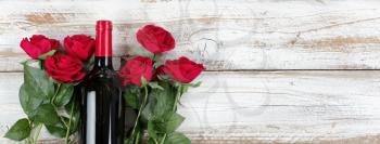 Romantic Valentines Day celebration with red wine and roses on white rustic wood 