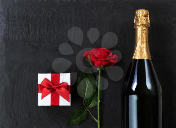 Anniversary background with champagne and gifts on natural black slate stone 