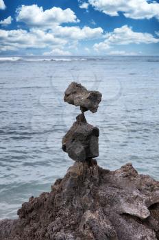 Native rocks stacked vertically with ocean and blue sky in background 