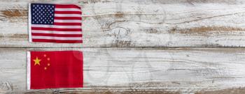 National flags representing China and the United States of America on white rustic wooden background. Trade war concept