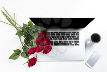 Red roses on work desktop for a love romance concept such as Valentines Day holiday 