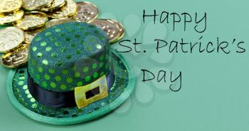 Close up of a St Patricks day Irish elf hat and shiny gold coins in background on green setting with copy space plus text message